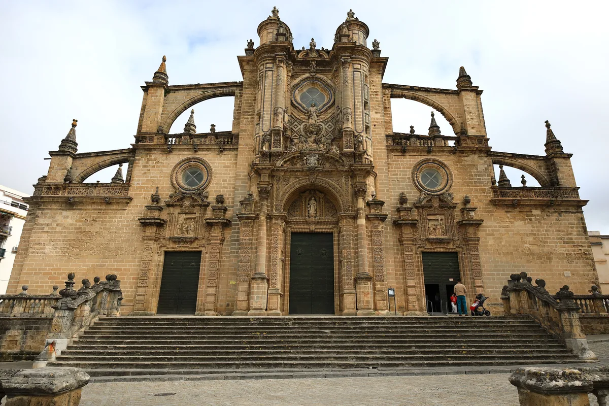 The stone façade of Jerez cathedral with twin towers, rose windows and a wide flight of steps